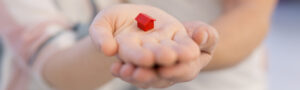 couple showing small red house in hands