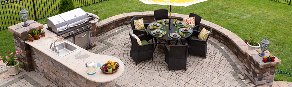 Outdoor dining area with built in grilling area and sink.