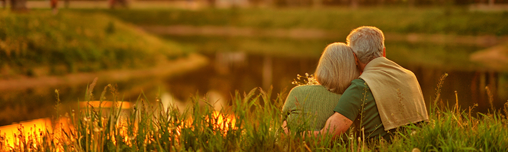 A retired couple enjoying a quiet moment together by a lake.