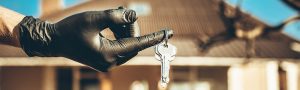A gloved hand holding a set of keys to a home.