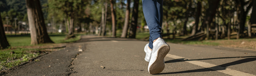 A woman walking on a paved trail.