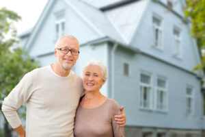 happy senior couple hugging over house background