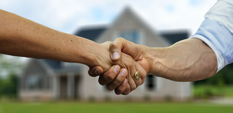 People shaking hands in front of a home