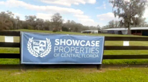 A Showcase Properties banner on the fence of a horse farm.