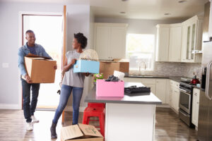 Man and woman moving boxes into their kitchen