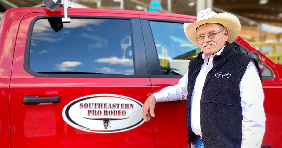 Ruben Lamb poses in front of his pick up truck, which has the Southeastern Pro Rodeo logo on the side. 