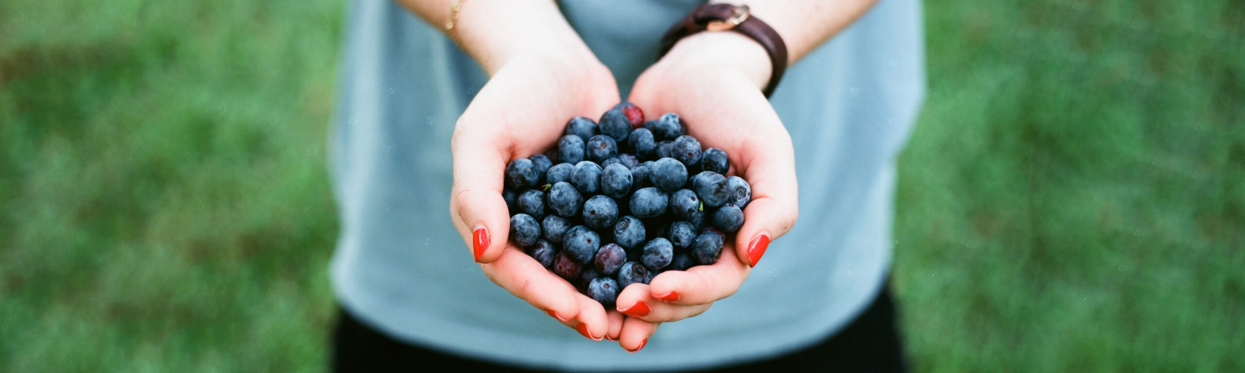 A woman holding two handfuls of blueberries.