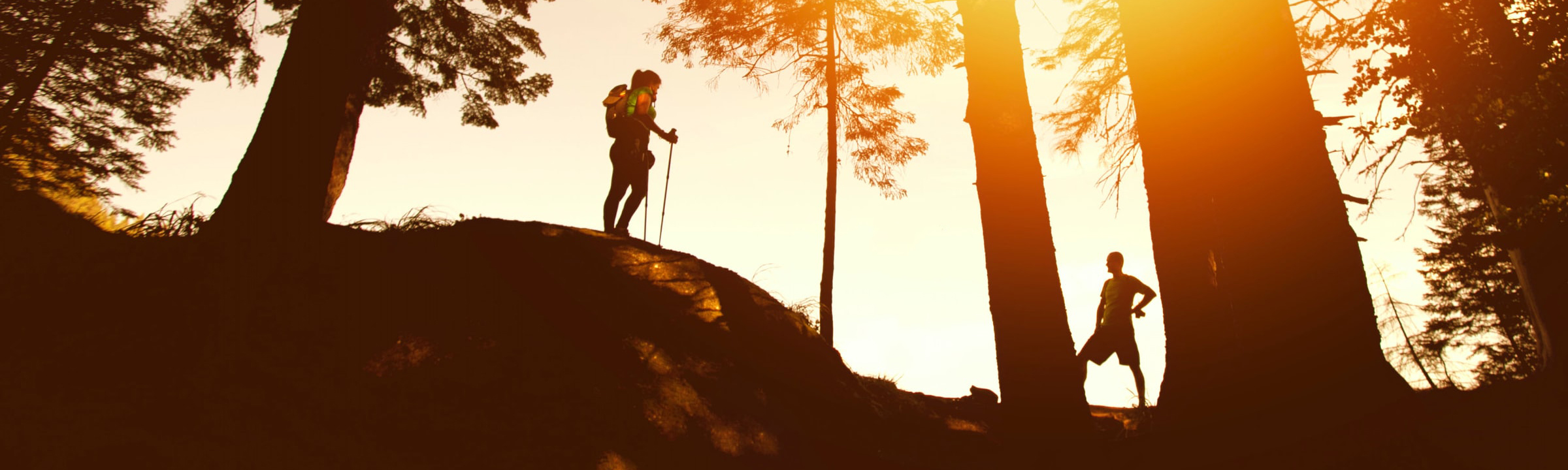 A couple hiking on a ridge at sunset.