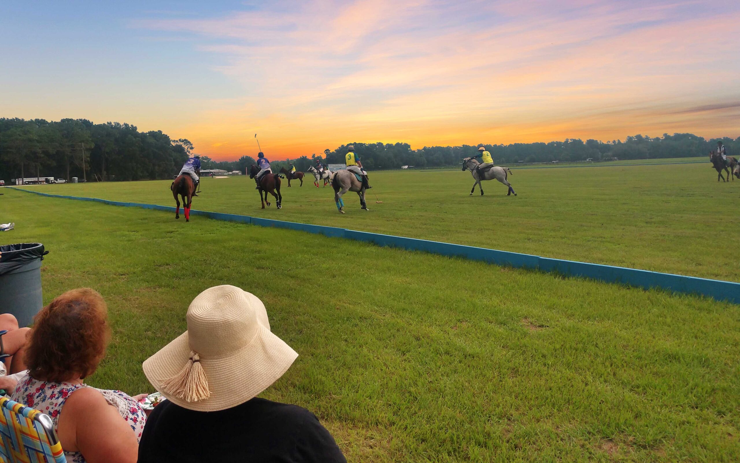 The polo players on the field at sunset.