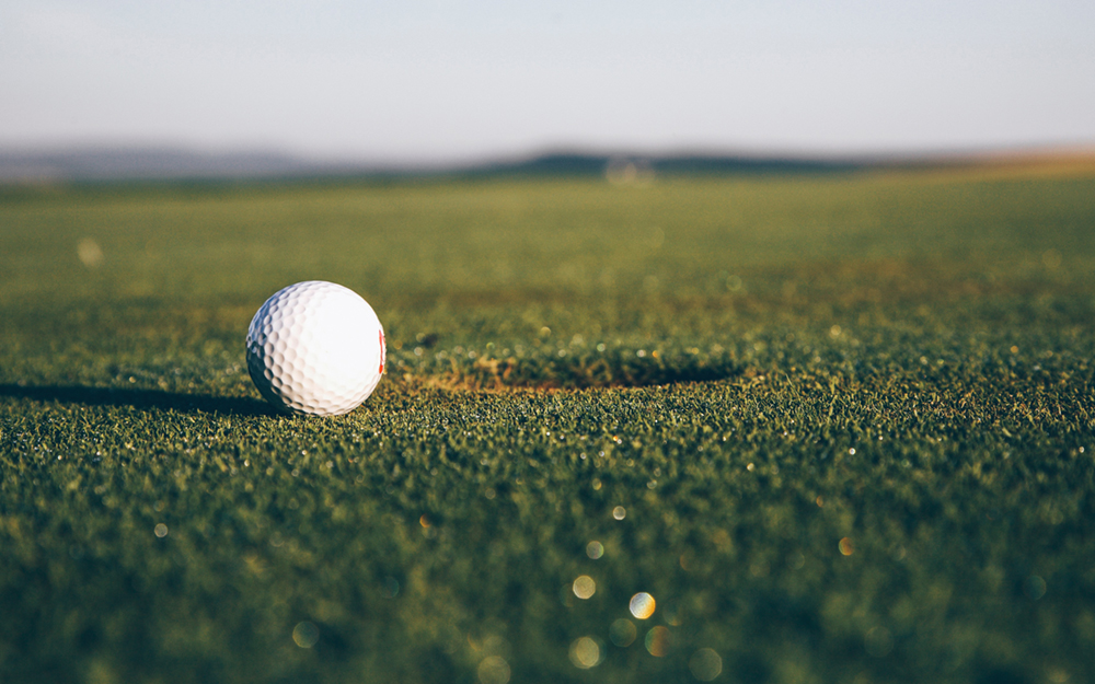 A golf ball about to go into the hole.