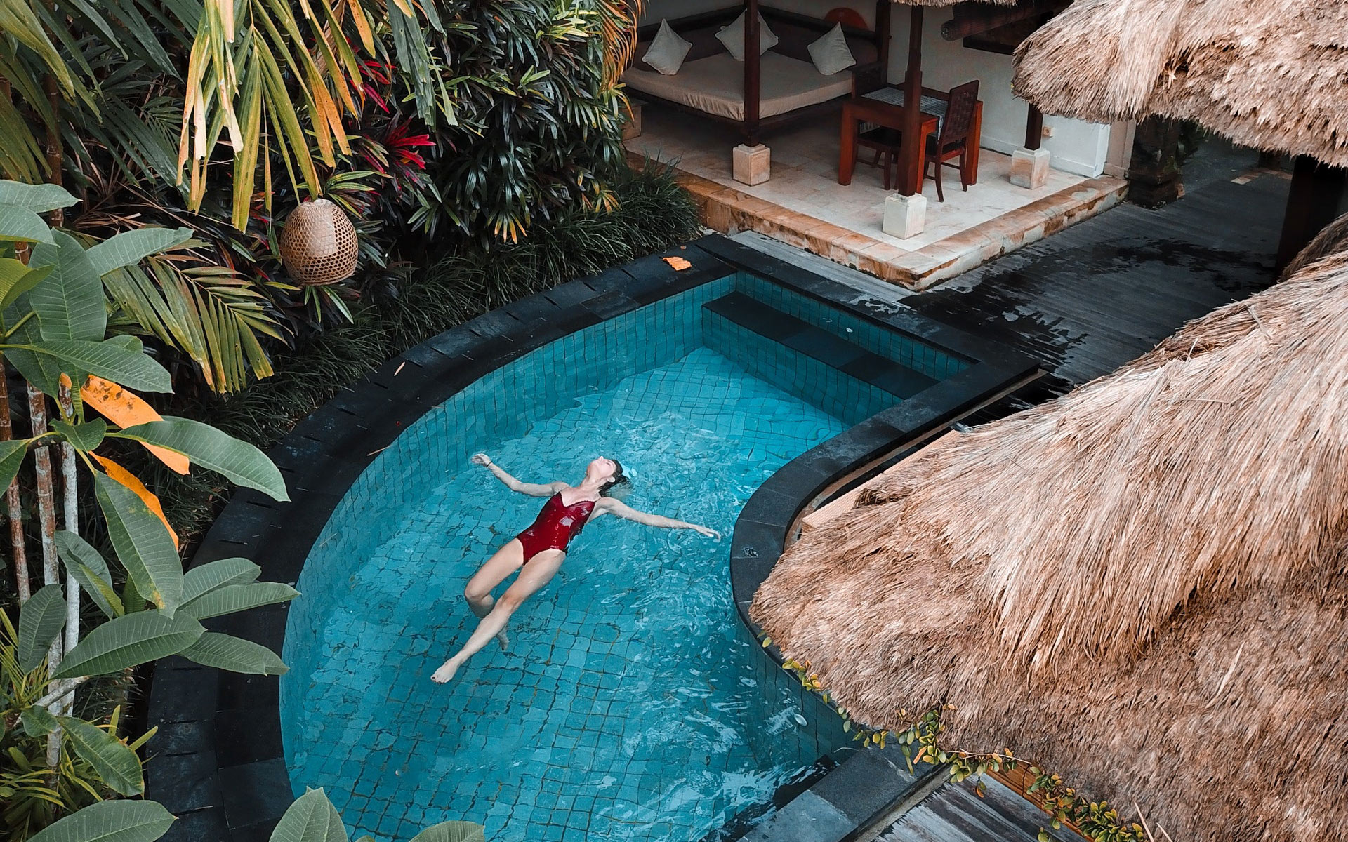 A woman swimming in a luxurious tropical pool.