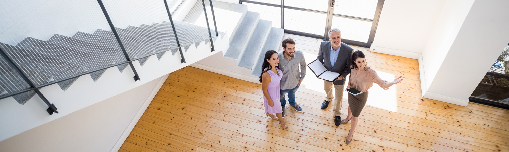 Realtors® showing a man and a woman a large home.