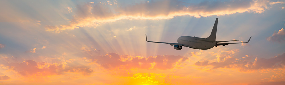 An airplane flying at sunrise or sunset.