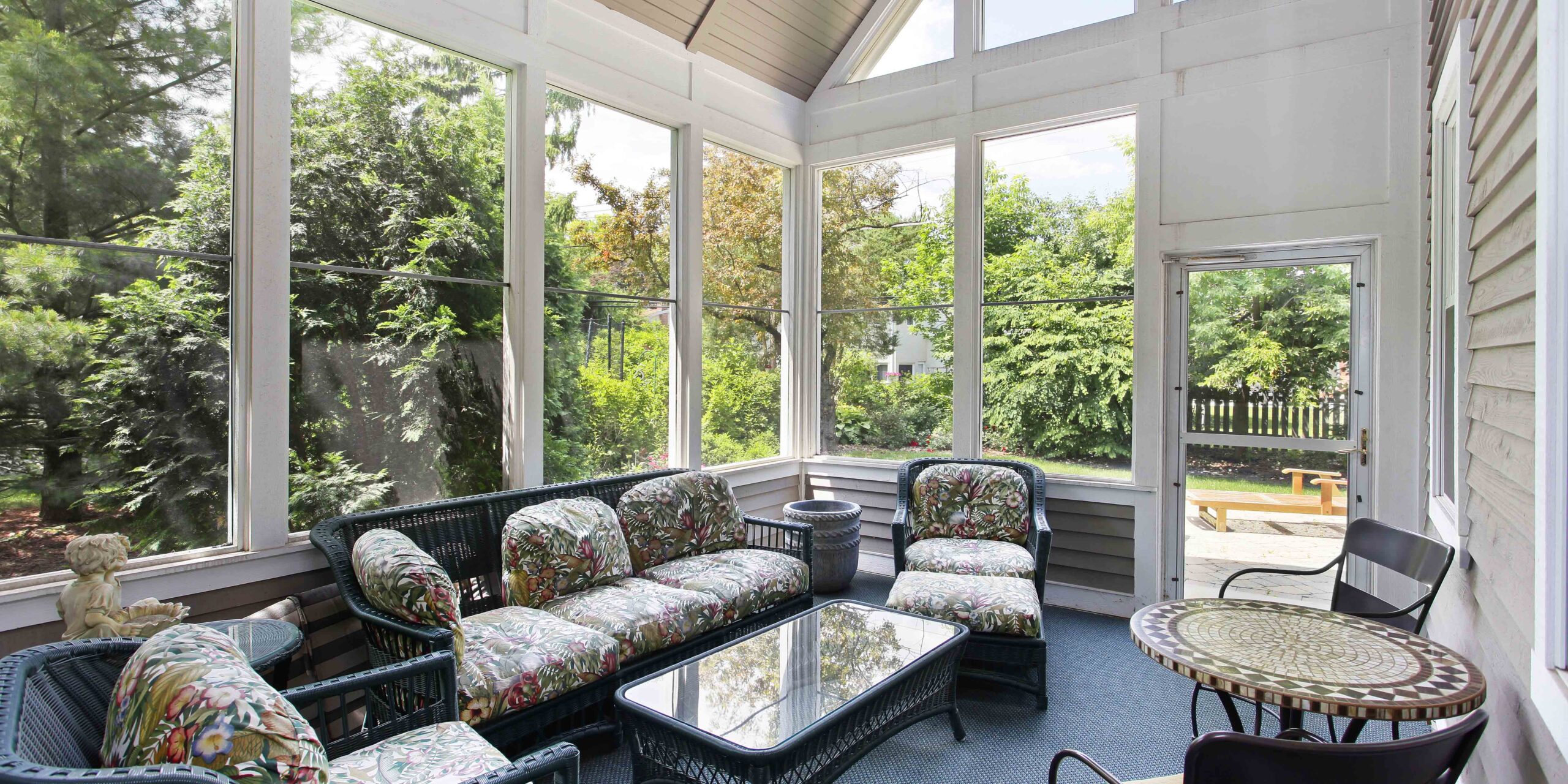 An attractive screen enclosed back porch with seating.