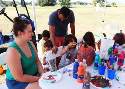 Parents watching their children paint pumpkins at the Fall Festival 2021