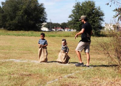 A man overseeing children in a potato sack race.