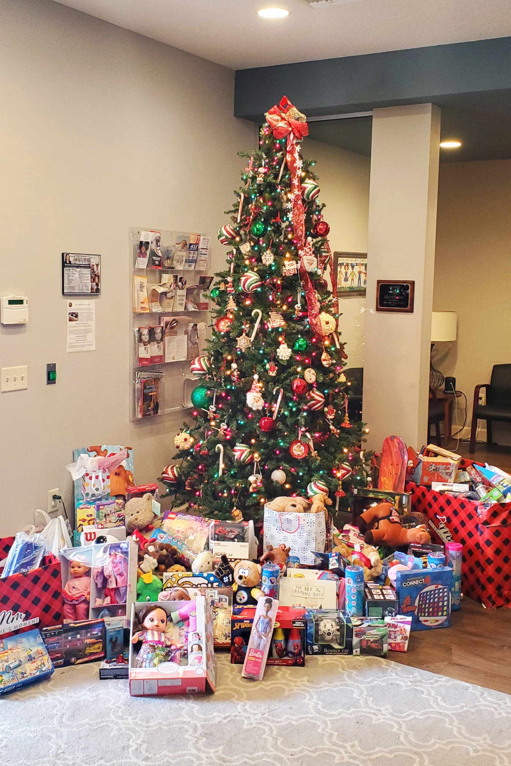 A beautifully decorated Showcase Properties Christmas tree with presents for the Mackenzie's Moment Toy Drive.