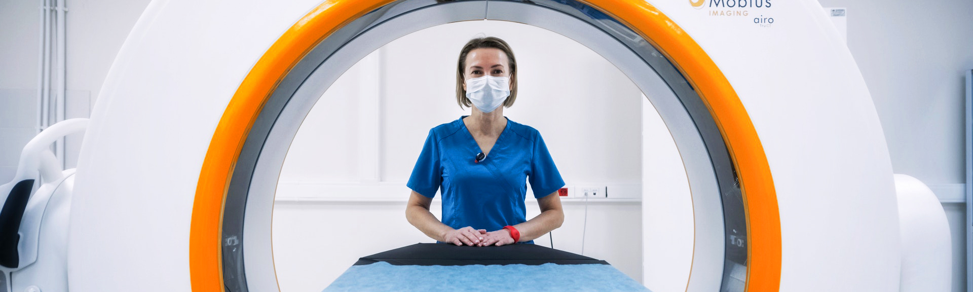 A female tech stands next to medical imaging equipment