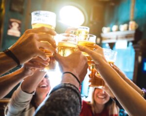 Happy people toasting with pilsner glasses of beer.