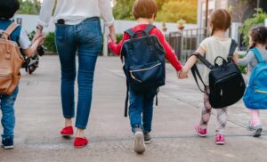 A woman leads a group of children to school.