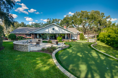 A home with a putting green in the backyard.