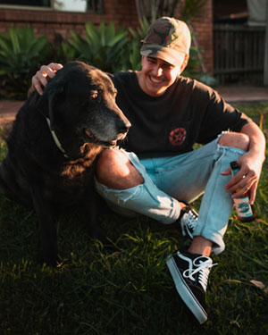 A man hangs out having a beer with his dog.