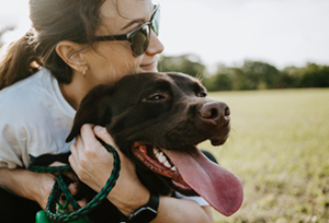 A woman hugs her black lab.