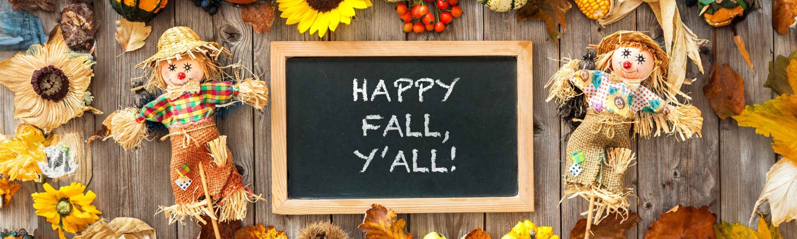 A table with fall theme and two scarecrows 