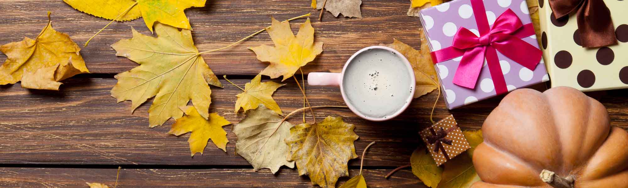 a table with autumn leaves and wrapped gifts