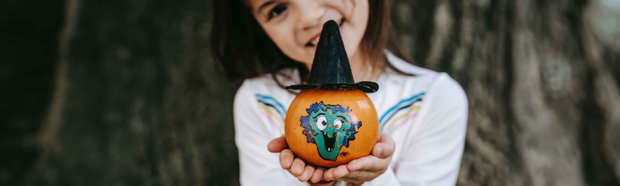 a girl holding a decorated mini pumpkin