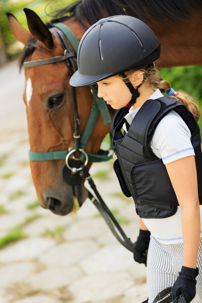 A young equestrian leads her horse.