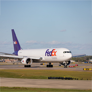 A fedex airplane taxiing on the runway.