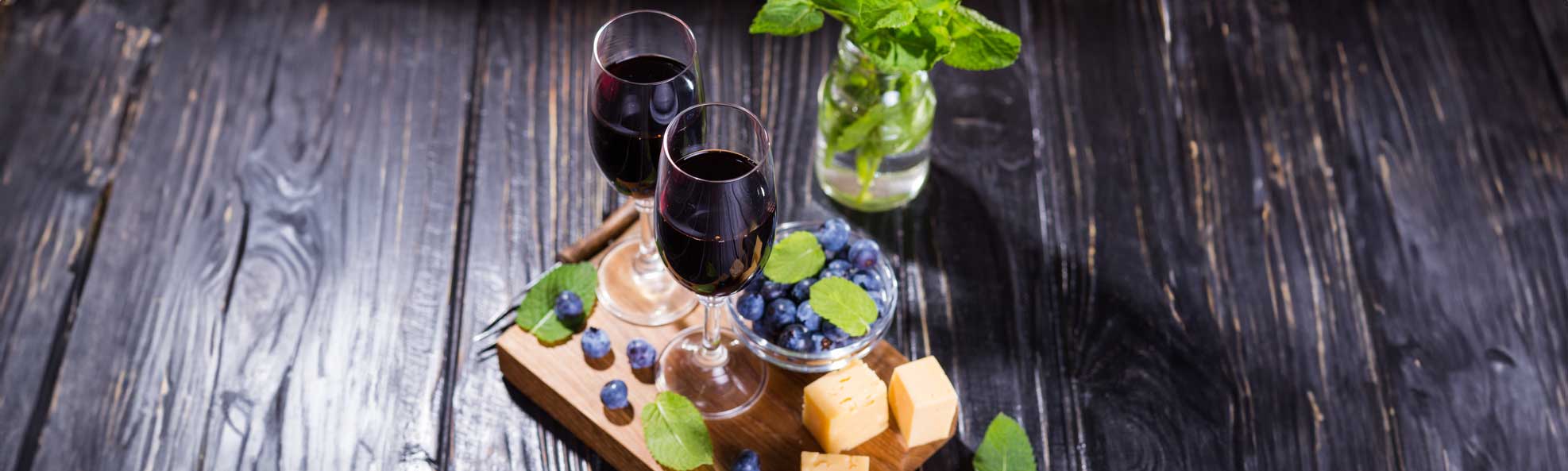 Glasses of blueberry wine, fresh blueberries, and cheese.