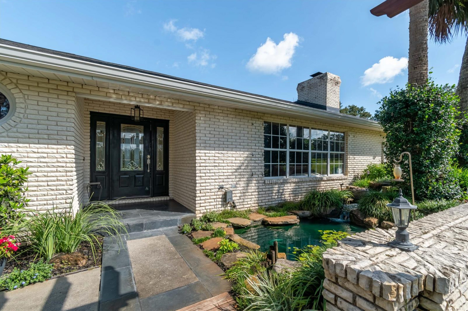 A luxurious pool area with plenty of room for seating, an attached hot tub and covered outdoor kitchen.